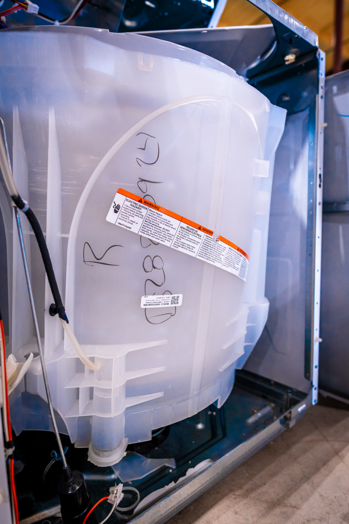 A close-up of a GE washer's control panel and a water hose.