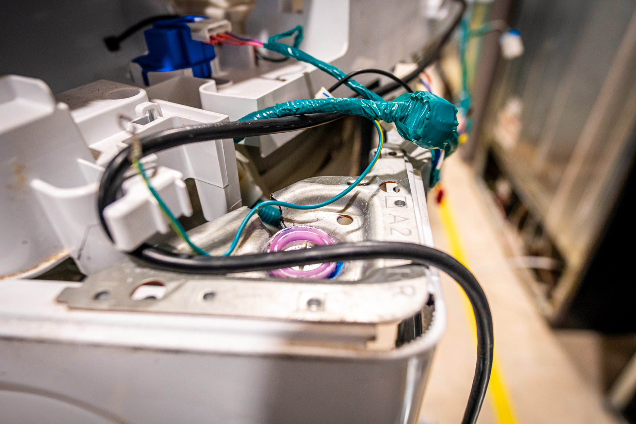 A technician listening for noises coming from a GE washer.