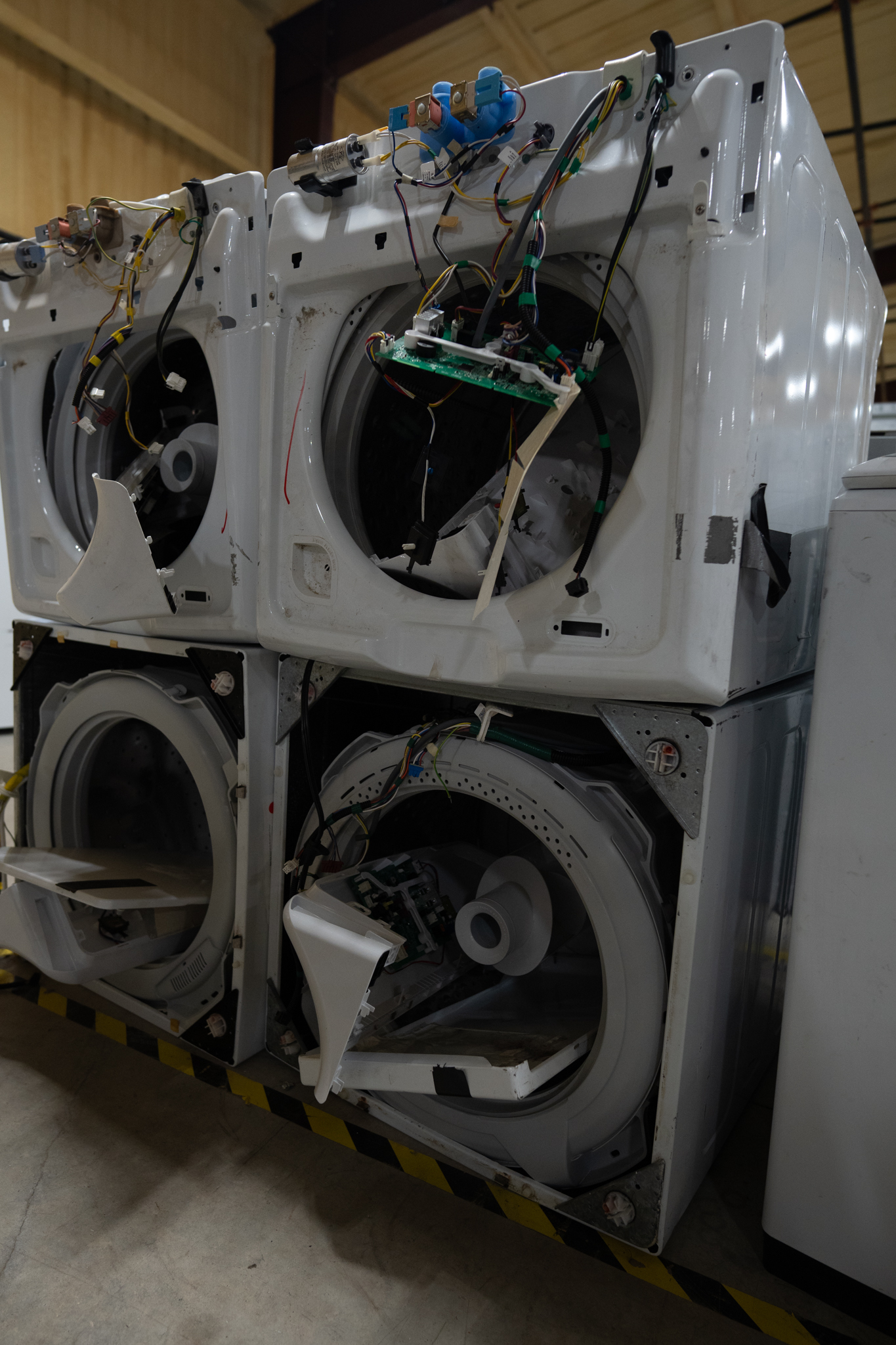 A technician working on the internal components of a GE washing machine.