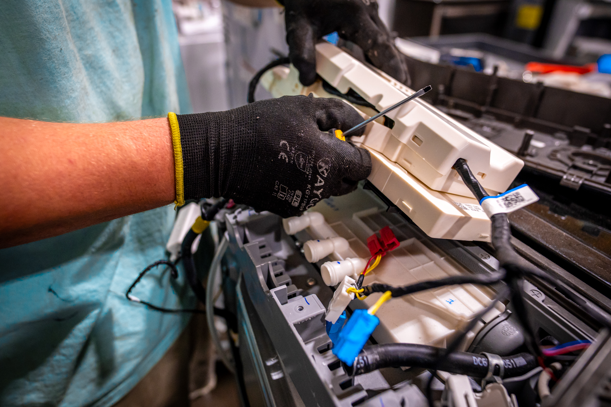 A technician inspecting a GE washer's drum for foreign objects.