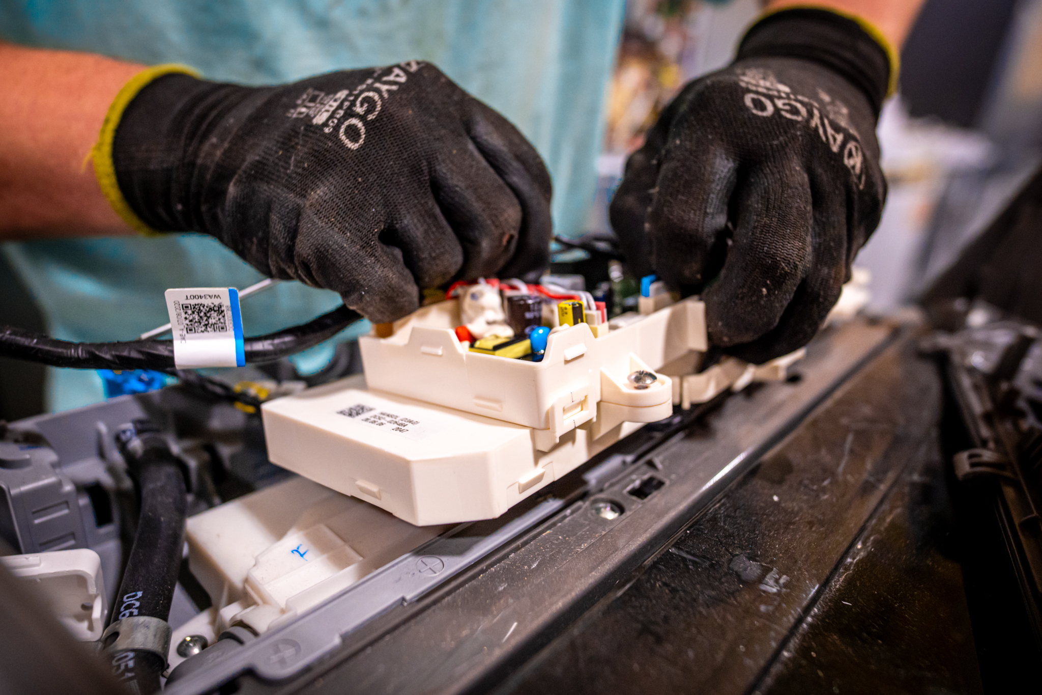 A technician examining the internal components of a GE washer.